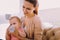 Careful woman looking at her baby while holding a bottle of water