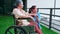 Caregiver asian woman care elderly sitting on wheelchair, consoling for encourage in garden at hospital.