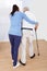 Caregiver assisting senior man to walk with stick