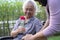 Caregiver daughter hug and help  Asian senior or elderly old lady woman holding red rose on wheelchair in park