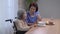 Caregiver feeding elderly asian woman with soup