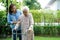 Caregiver help Asian elderly woman disability patient walk with walker in park, medical concept