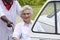 Caregiver helping a disabled lady to get into the car