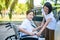 Caregiver helping senior handicapped asian woman from wheelchair get into car