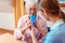 Caregiver helping senior woman drinking giving her a cup of water