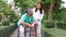 A caregiver helps support an elderly Asian woman holding a walking cane