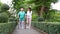 A caregiver helps support an elderly Asian woman holding a walking cane for exercise