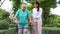 A caregiver helps support an elderly Asian woman holding a walking cane for exercise