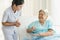 Caregiver nurse helping elderly woman taking medicine on the bed and check up after admit inpatient in hospital