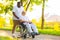 Caregiver and old man in a wheelchair. Professional nurse and patient walking outdoor in the park at sunset. Assistance