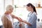 Caregiver putting gel on elbow of retired woman