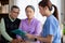 Caregiver sitting on sofa checkup and diagnostic with elderly couple patient about health in living room.