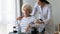 Caregiver supporting unhappy disabled older woman sitting in wheelchair