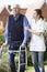 Carer Helping Senior Man To Walk In Garden Using Walking Frame