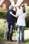 Carer Helping Senior Woman To Walk In Garden Using Walking Frame