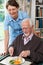 Carer Serving Lunch To Senior Man