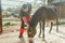 Caretaker with down syndrome taking care of animals in zoo, stroking donkey. Concept of integration people with