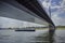 A cargo boat passing under the Oberkasseler bridge in Duseldorf, Germany on a cloudy day.