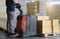 Cargo boxes shipment, Worker working with electric forklift pallet jack unloading cardboard boxes on pallet in the warehouse.