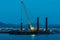 Cargo crane working in small port, construction of industrial harbor or dock in evening, sea goods transportation and