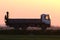 Cargo dump truck driving on highway hauling goods in evening. Delivery transportation and logistics concept