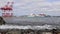 Cargo port of Halifax.  Big cargo ship leaves harbor. Cranes loading cargo ship. light waves cloudy sky.