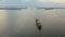 Cargo ship bulk-carrier with wood logs on board, floats out of the bay to the sea, aerial view