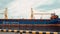 Cargo ship with containers and a crane departs from the pier.