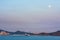 Cargo ship leaving the port of Santos during sunset with a full moon rising