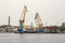 Cargo ship loading cranes in industrial zone on river, freight logistic transportation by water concept