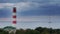 Cargo ship passes by a beautiful majestic lighthouse