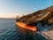 Cargo ship run aground at sea coastline. Shipwreck accident of nautical vessel after huge sea storm, aerial view