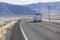 Cargo trailer being pulled down an empty highway stretching for miles into the desert