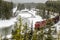 Cargo Train along an Icy River during a Heavy Snowfall