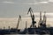 Cargo transportation industrial landscape - seaport at sunny day - cranes in harbor, silhouette