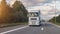 Cargo truck with cargo trailer driving on a highway. White Truck delivers goods in early hours of the Morning - very low angle