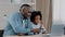 Caring african american father helping little daughter schoolgirl do homework adult parent or tutor explaining to child
