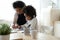 Caring African American mother helping to little daughter with homework