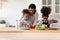 Caring biracial mom teach little kids cooking at home