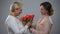 Caring daughter giving red tulips to mature mother, international women day