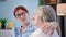 caring for the elderly, female social worker comforting mature woman while sitting on sofa in room