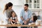 Caring father and mother playfully teaching little children to cooking.