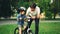 Caring father is putting safety helmet on his little son`s head then teaching happy boy to ride bicycle while loving