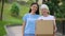 Caring female activist hugging old woman donation card box, social volunteering