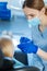 Caring female dentist examining little patients mouth cavity