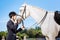 Caring female rider loving her white horse greatly