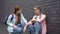 Caring female teenager supporting lonely classmate sitting aside, offering help