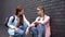 Caring female teenager supporting lonely classmate sitting aside, offering help