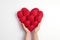 A caring gesture of hands cupping a collection of velvet red hearts, representing compassion and heartfelt generosity on