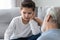 Caring grandfather calming, talking with upset little grandson